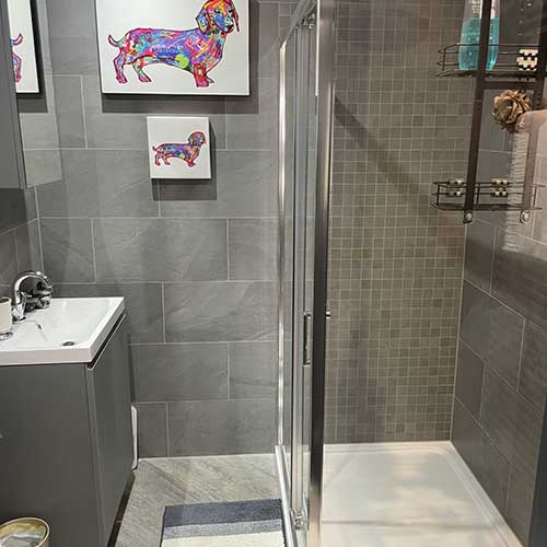 Grey-tiled bathroom with walk-in shower enclosure and vanity basin