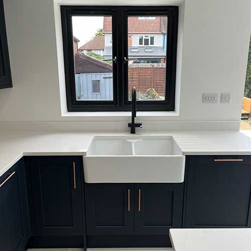 Navy shaker kitchen with butler sink below window