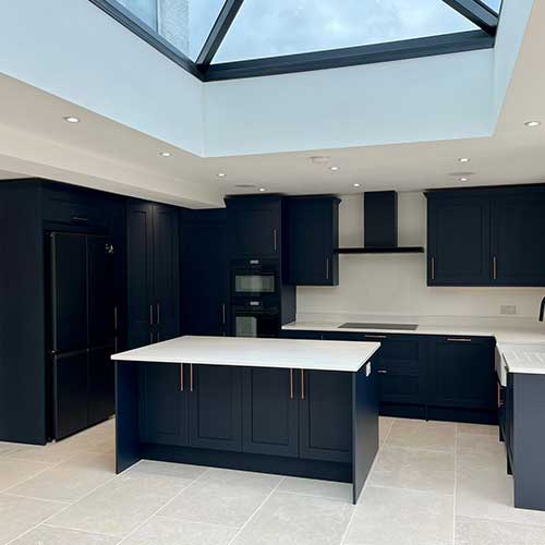 Navy kitchen with island beneath a lantern roof skylight