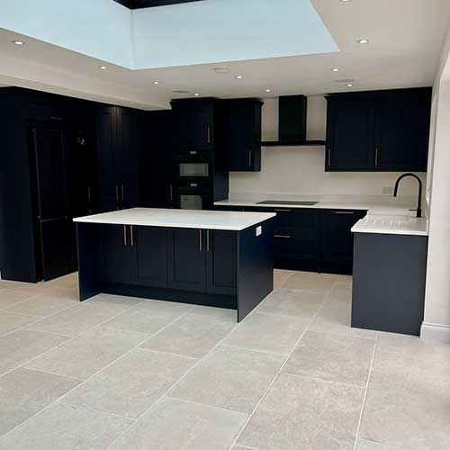 Open-plan navy kitchen with roof lantern and tiled floor