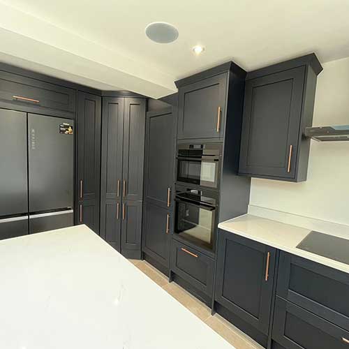 Navy kitchen units with built-in ovens and American fridge