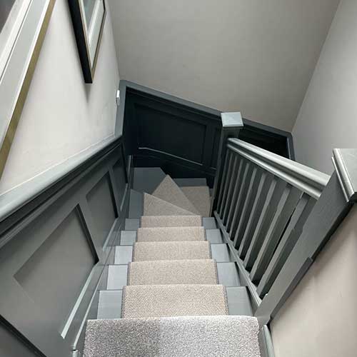Loft staircase with grey panelled walls and carpet runner