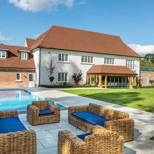 Large rendered and brick country house with oak-framed garden room and pool