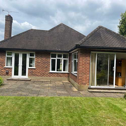 Rear of tiled brick bungalow with French doors and sliding patio doors