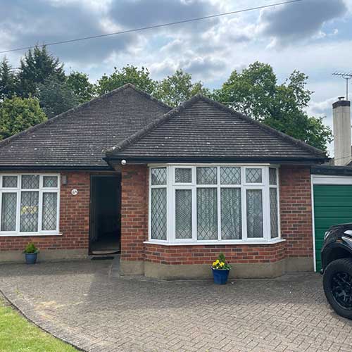 Front of brick bungalow with bay window, garage and block paved drive