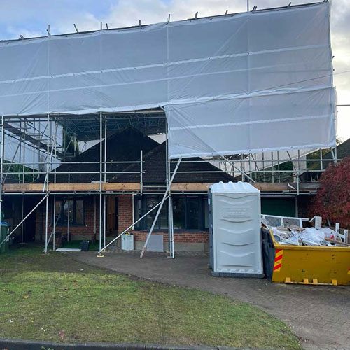 House with scaffolding and monoflex sheeting for roof works