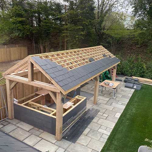 Slate roof being laid on oak-framed garden building