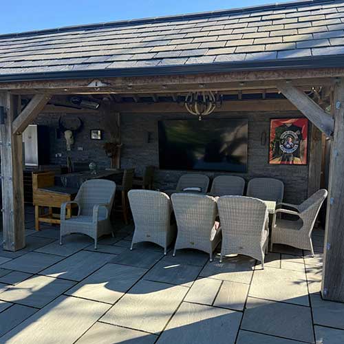 Covered outdoor dining area under oak-framed garden building