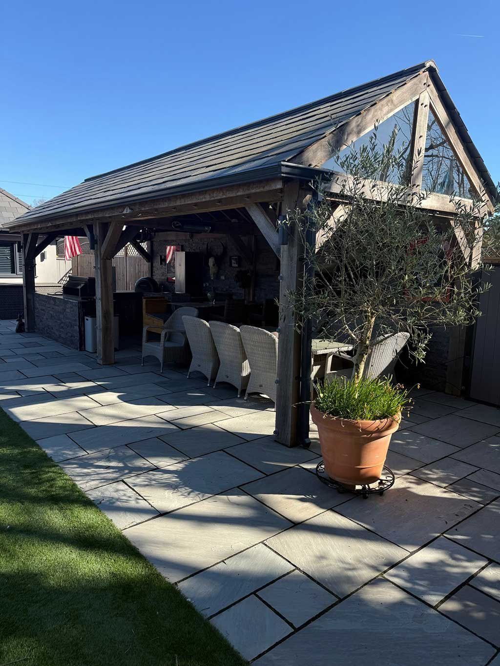 Completed oak framed garden room with a slate roof and patio