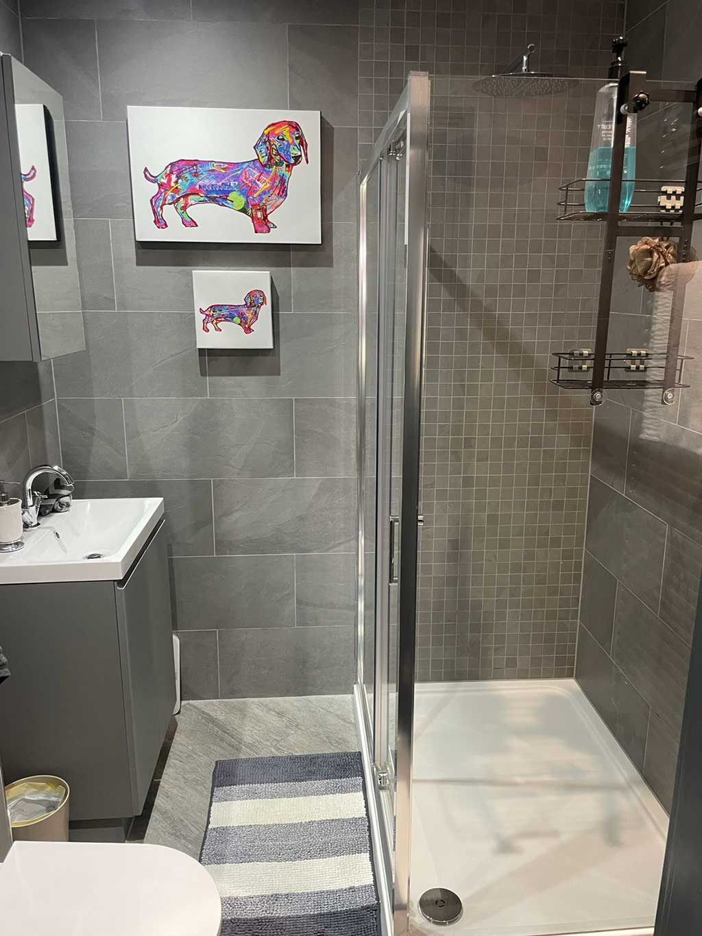 Grey tiled bathroom with a walk in shower enclosure and vanity basin