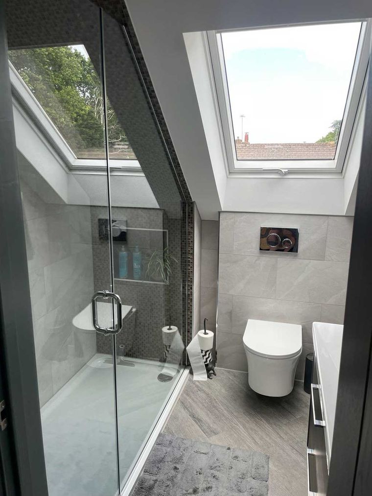 Loft en suite shower room with a tiled walk in shower and rooflight