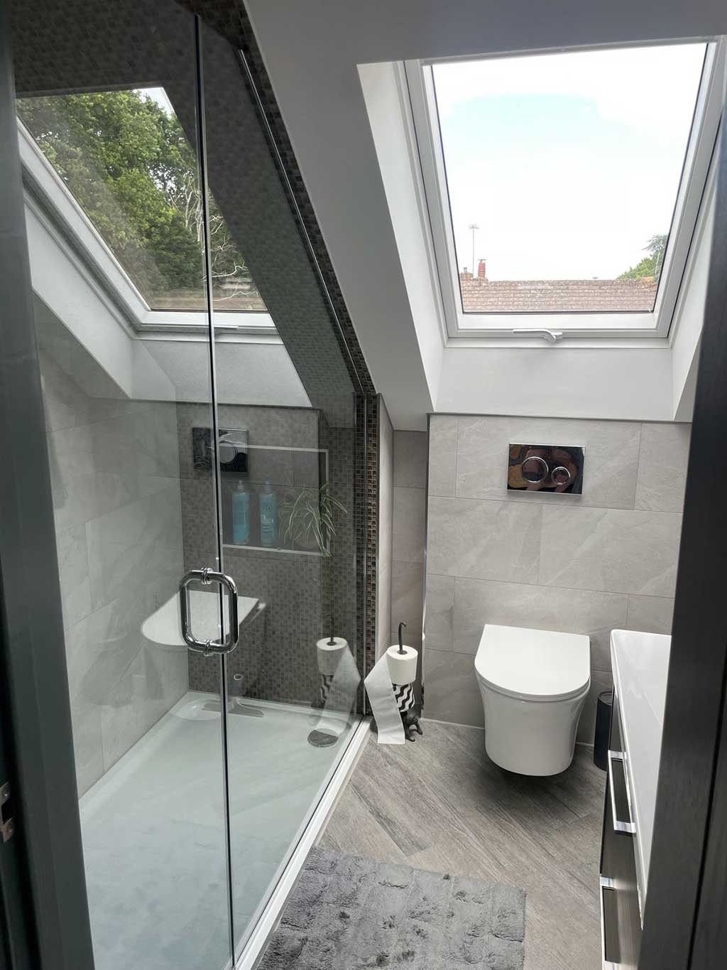 Loft en suite shower room with a tiled walk in shower and rooflight