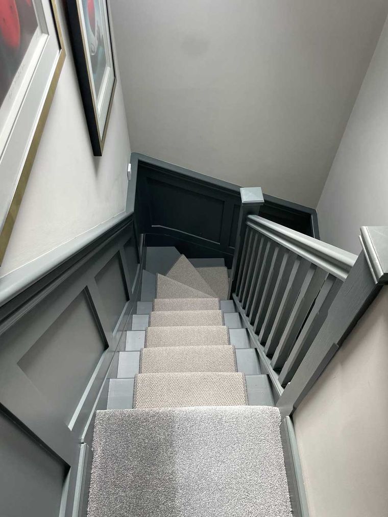 Loft staircase with grey panelled walls and a carpet runner
