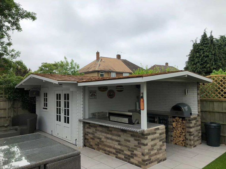 Garden room and outdoor kitchen under a pitched shingle roof canopy