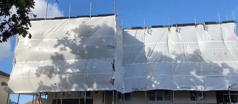 House wrapped in scaffolding and sheeting during loft conversion roof works