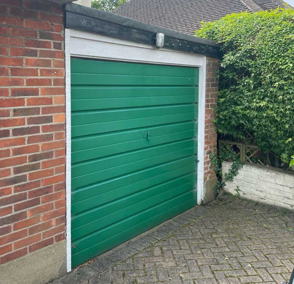 Attached brick garage with an up and over door on a block paved drive